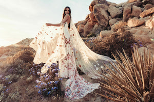 Inspired by desert blossoms in spring, Cora’s fully embroidered, vibrant florals are set on sand-dyed tulle to amplify the beautiful contrast of blooms throughout a bare terrain. A fully boned bodice wraps the body for ultimate support, balanced by a dramatic train with cascading embroidered florals. A playful take on a classic silhouette, Cora’s bright palette is perfect for the bride wanting to infuse colour into their celebrations.