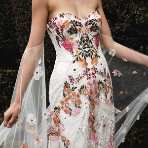 Inspired by desert blossoms in spring, Cora’s fully embroidered, vibrant florals are set on sand-dyed tulle to amplify the beautiful contrast of blooms throughout a bare terrain. A fully boned bodice wraps the body for ultimate support, balanced by a dramatic train with cascading embroidered florals. A playful take on a classic silhouette, Cora’s bright palette is perfect for the bride wanting to infuse colour into their celebrations.