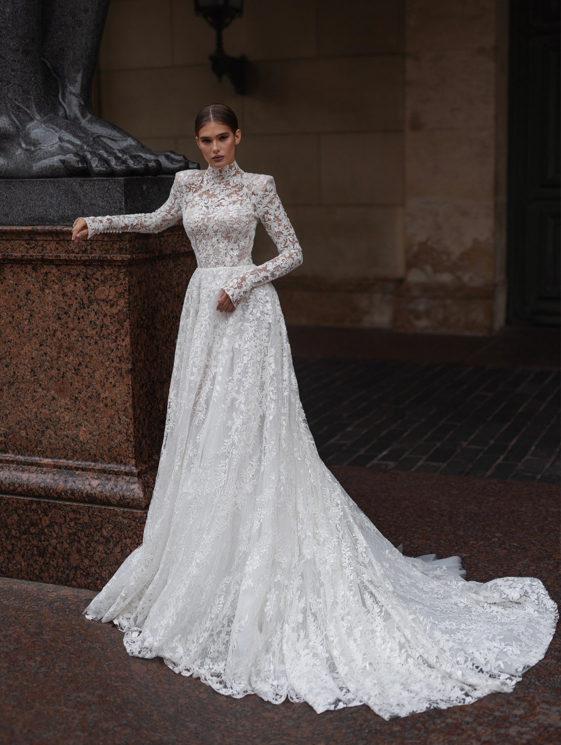 The Lidia Gown is the perfect wedding dress for the modern bride. With a flattering A-line silhouette, elegant long sleeves, and a high collar neckline, this gown is made from delicate lace and embellished with stunning sequins. Make a statement on your special day with this one-of-a-kind gown.