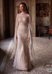 Feel like a goddess in the Asteria Gown! This magnificent mermaid wedding dress features a stunning illusion neckline adorned with intricate beadwork that catches the light in all the right places. The illusion back adds a touch of elegance and the detachable tulle cape, embellished with matching beadwork and fringes, allows you to customize your bridal look. Shine on your special day with the Asteria Gown!