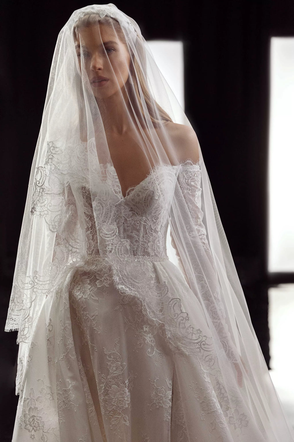 This Bernita Gown exudes elegance with its exquisite French lace and romantic allure. The accompanying veil adds a touch of chic and completes the bridal look. Perfect for any sophisticated bride seeking a timeless and refined wedding gown.