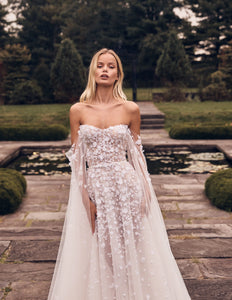 Introducing the Robe Margot - a stunning A-line gown with a delicate sweetheart corset and a sophisticated beaded degrade. Accompanied by a lightly embellished of-the-shoulder cape, this gown exudes elegance and grace. Perfect for formal events and special occasions.