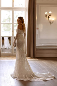 This Marcela Dress features stunning sequins adorning the entire mermaid-style silhouette, making it the perfect choice for a glamorous wedding look. The intricate detailing and form-fitting design will highlight your curves, while the sparkling embellishments add a touch of luxury. Make a statement on your special day with this gorgeous dress.