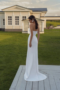 Elevate your special day with our Limanta Gown. This figure-hugging wedding dress features an asymmetrical bodice and a skirt with a stunning slit. The back zipper ensures a perfect fit. Crafted from fine satin, lace, and sequins, this gown will make you shine on your big day!