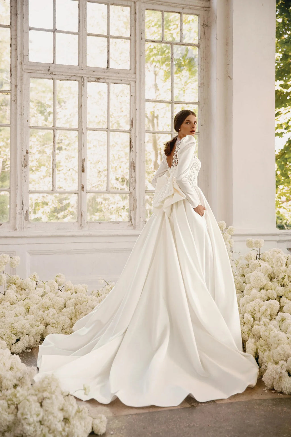 The Rosalee Gown is a breathtaking A-line wedding dress made of luxurious silk satin. The stunning corset features a unique draped design and voluminous puffed sleeves, while delicate hand-embroidered lace adorns the neckline and waistline. With hidden pockets and a removable sash, this dress effortlessly combines elegance and practicality.