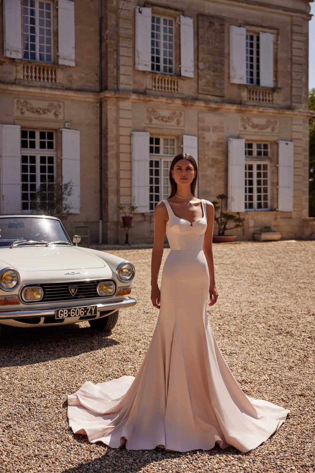 The Ellie Gown is the perfect choice for a sophisticated and modern bride. Made with elegant champagne pink elastic satin, this mermaid silhouette dress features a bustier corset with straps and a flattering geometric neckline. The skirt is fitted with intricate reliefs and a long train, creating a stunning and unique look for your special day.