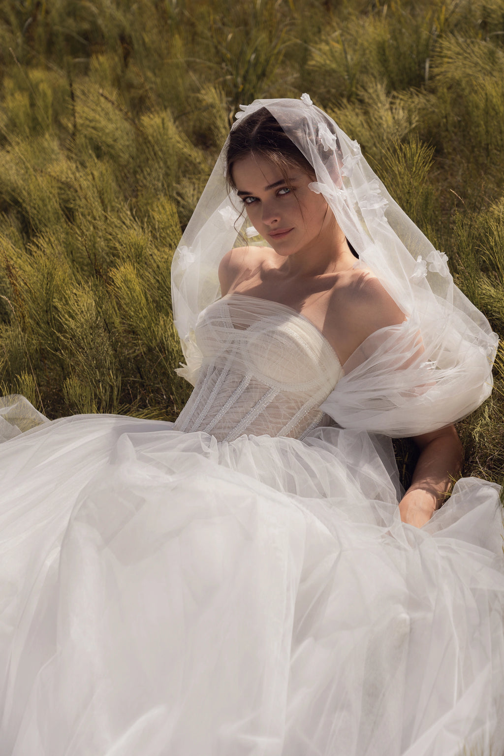 Experience the elegance and beauty of the Emfira Gown. This A-line wedding dress features voluminous cascading straps and a zippered back. Made with delicate tulle and sparkling glitter, your special day will be simply magical.