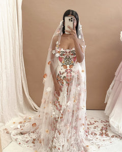 Inspired by desert blossoms in spring, Cora’s fully embroidered, vibrant florals are set on sand-dyed tulle to amplify the beautiful contrast of blooms throughout a bare terrain. A fully boned bodice wraps the body for ultimate support, balanced by a dramatic train with cascading embroidered florals. A playful take on a classic silhouette, Cora’s bright palette is perfect for the bride wanting to infuse colour into their celebrations.