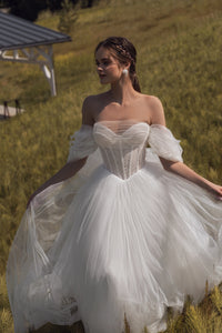 Experience the elegance and beauty of the Emfira Gown. This A-line wedding dress features voluminous cascading straps and a zippered back. Made with delicate tulle and sparkling glitter, your special day will be simply magical.