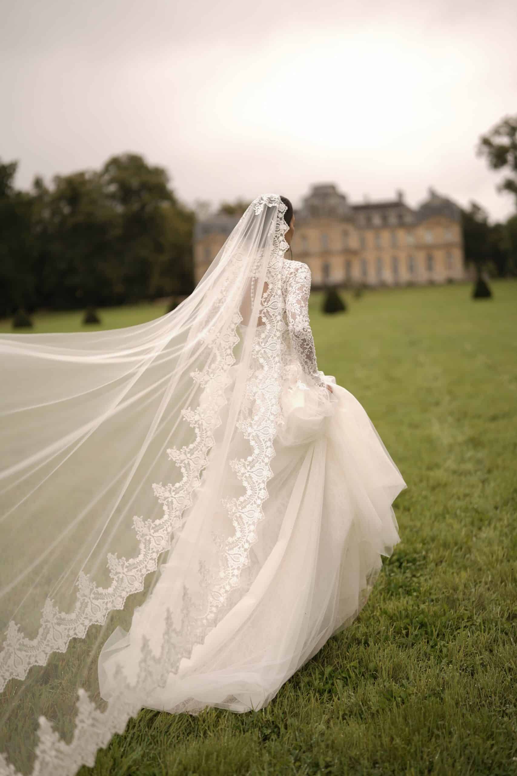 A sweetheart corset mermaid gown made from luxurious lace and decorated with pearls, featuring semi-sheer cutouts. It is accompanied by a dramatic detachable corset overskirt and a lace topper for a complete ensemble.