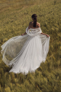 Experience the elegance and beauty of the Emfira Gown. This A-line wedding dress features voluminous cascading straps and a zippered back. Made with delicate tulle and sparkling glitter, your special day will be simply magical.