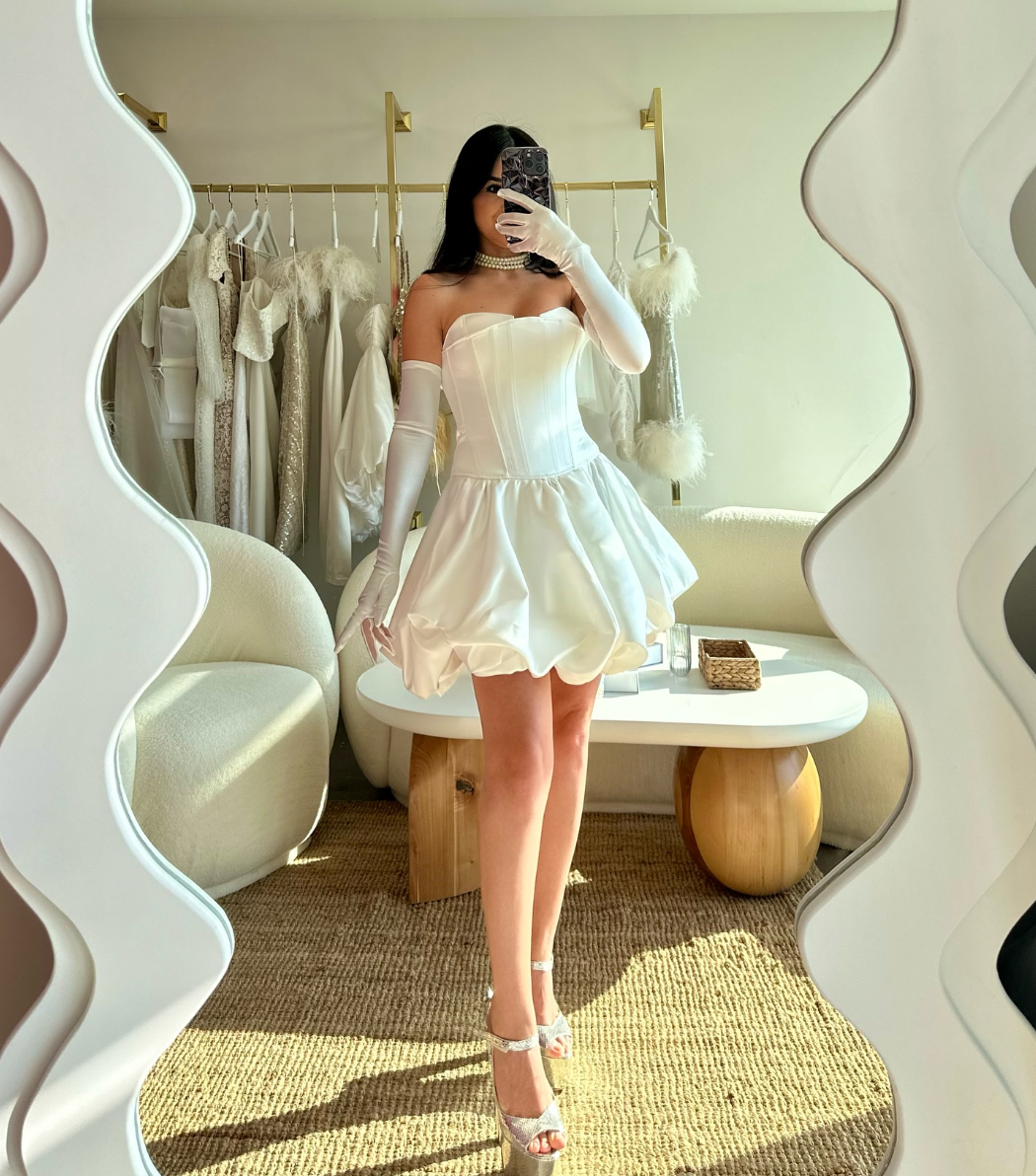 Elevate your special day with the luxurious Carmen Mini Dress. This strapless, princess style mini dress is custom made and features elegant draping for a formal touch. Perfect for the bride who wants to make a statement!