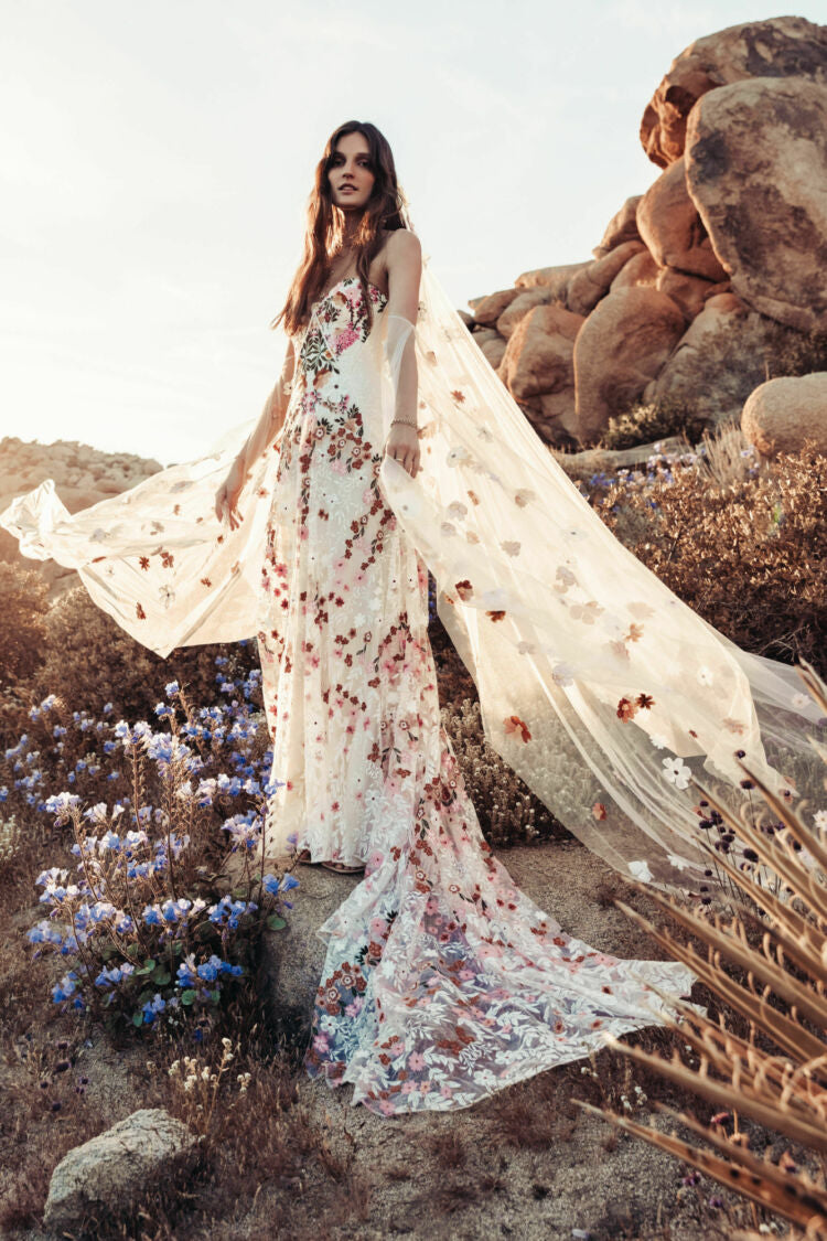 Inspired by desert blossoms in spring, Cora’s fully embroidered, vibrant florals are set on sand-dyed tulle to amplify the beautiful contrast of blooms throughout a bare terrain. A fully boned bodice wraps the body for ultimate support, balanced by a dramatic train with cascading embroidered florals. A playful take on a classic silhouette, Cora’s bright palette is perfect for the bride wanting to infuse colour into their celebrations.