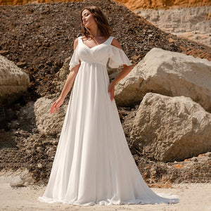 The Robe Minette is a stunning and elegant A-line wedding dress. The cape sleeves, made of delicate chiffon, add a touch of femininity and grace. The low back and sweep train create a simple yet alluring silhouette. Perfect for the modern and sophisticated bride.