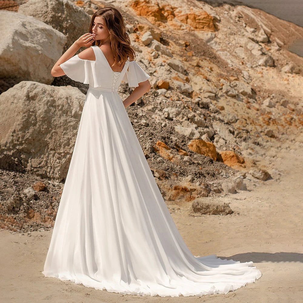 The Robe Minette is a stunning and elegant A-line wedding dress. The cape sleeves, made of delicate chiffon, add a touch of femininity and grace. The low back and sweep train create a simple yet alluring silhouette. Perfect for the modern and sophisticated bride.