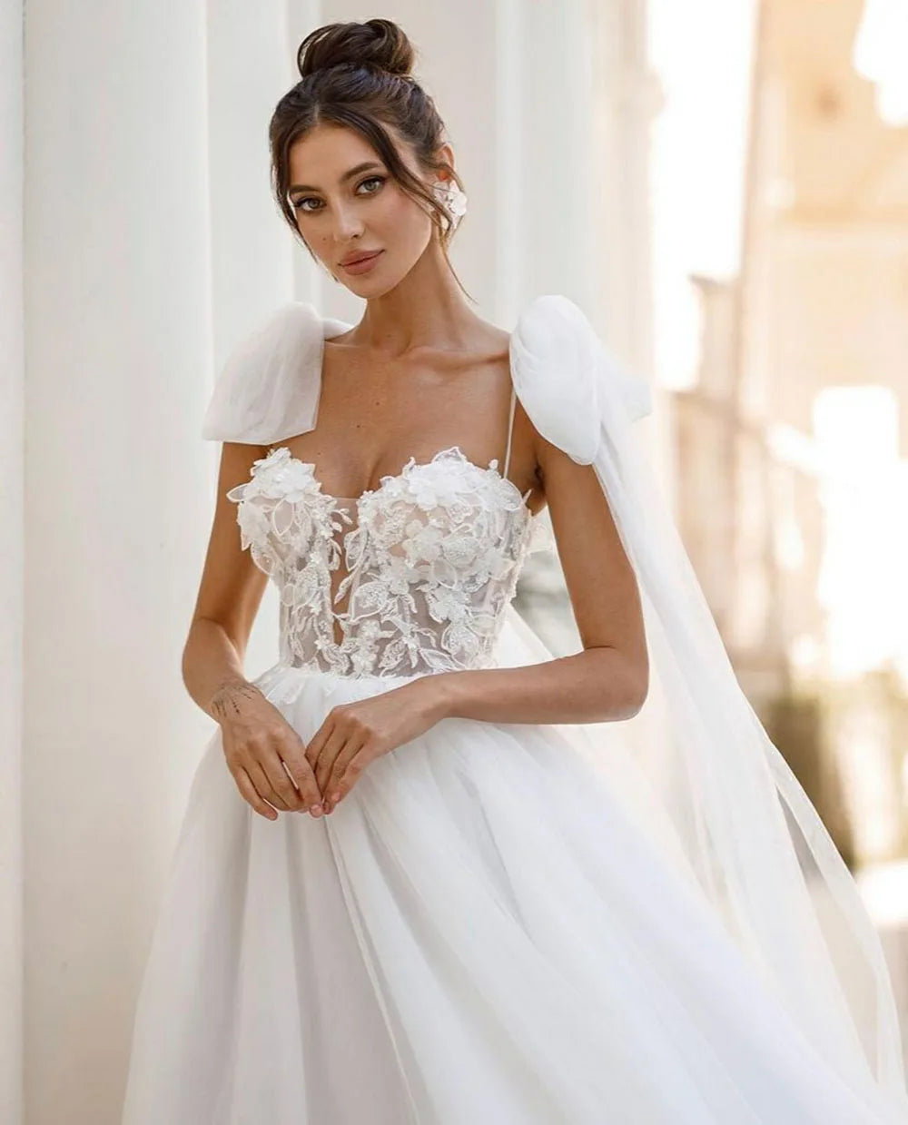 Introducing the Robe Allura - a stunning luxury lace wedding dress with delicate shoulder bows and elegant lace appliques. Designed in a flattering A-line silhouette, this dress is perfect for princess brides with a bohemian touch. Look and feel like a true wedding day princess in this breathtaking gown.