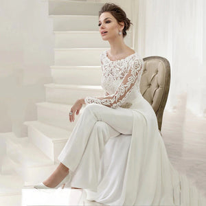 Elegance and versatility combine in our Combinaison Madisson. From the modest long sheer sleeves to the stunning lace detailing, this custom-made jumpsuit is perfect for the modern bride. The detachable skirt train adds a touch of drama, allowing you to seamlessly transition from ceremony to reception.