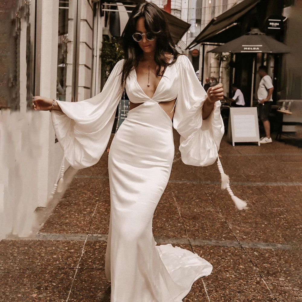 Indulge in the luxurious elegance of the Robe Suzanne. Featuring long bishop sleeves, an open back, and a side cutout, this custom-made wedding gown is made of flowing chiffon, accentuating every curve. With a sexy V-neck design, this dress is perfect for the modern bride looking for a simple yet stunning look.