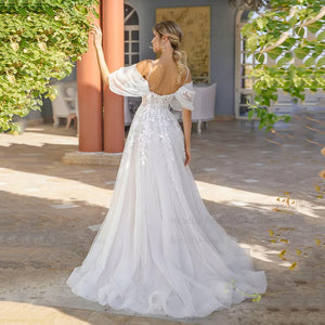 The Dress Harper is a beautiful A-line wedding dress with a boho flair. The V-neckline and lace appliques add a touch of elegance, while the spaghetti straps and side split bring a sexy element. Made with soft tulle, this dress also features a sweep train for a dramatic effect. Perfect for a stylish and modern bride looking for a unique and flattering gown.