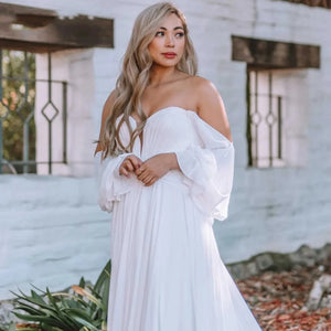 Dare to be different on your special day with the Robe Capucine. This Sirene Boho Off Shoulder Wedding Dress boasts a chic V-neck and stylish chiffon material. The side split, cut out design, and backless look add a touch of uniqueness. Plus, the pleats, button accents, and court train offer a dreamy, ethereal feel.