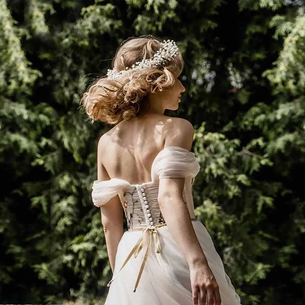 The Robe Giuliana is a stunningly crafted wedding dress, featuring intricate boho embroidery and delicate tulle blossom details. The dress boasts a sweet off shoulder neckline, adding a touch of romance to any wedding look. Exude elegance and grace on your special day with this beautiful and unique piece.