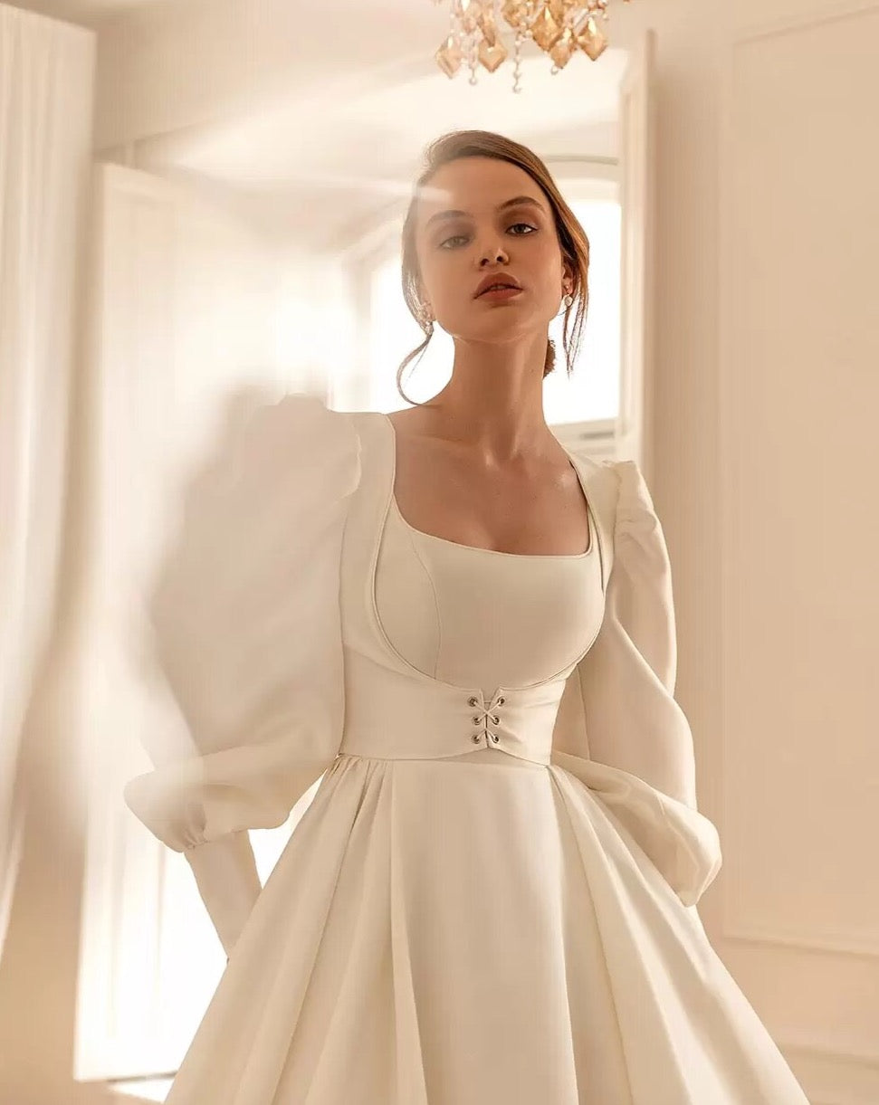 Feel like a princess on your special day with our Robe Sancia. The square neckline and full, long sleeve puff design adds elegance to the A-line silhouette. This two-piece bridal gown is perfect for any bride, ensuring a stunning and timeless look