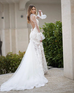 Elevate your bridal style with the Robe Pascale. This boho mermaid wedding dress features a V-neckline and puff long sleeves for a unique and elegant look. Made with high-quality materials, it offers both comfort and style on your special day. Embrace your inner mermaid and make a statement with this stunning bridal gown.