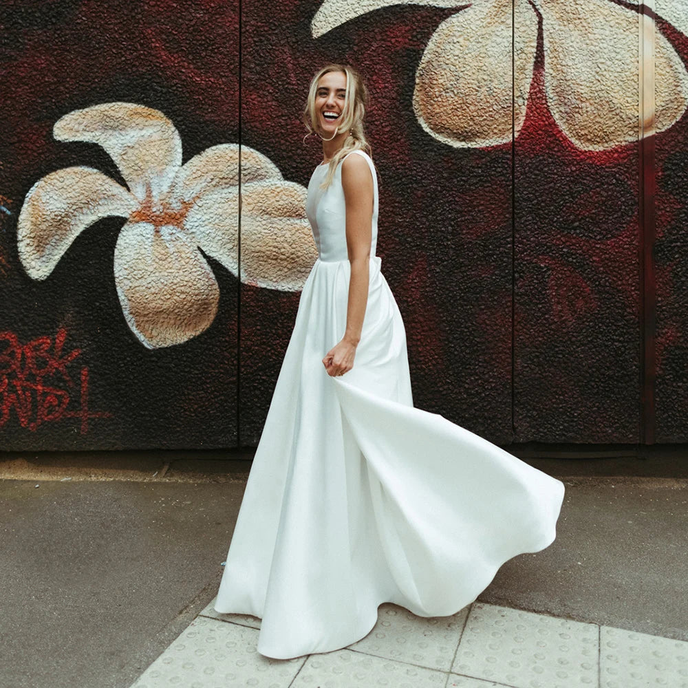 This elegant Ila Robe features a square open back, illusion V neckline and classic satin fabrication for that extra bit of sophistication. The intricate brush train adds a timeless touch and is custom-made to your exact measurements for a flawless fit. Feel like a princess on your special day with this beautiful bridal gown.