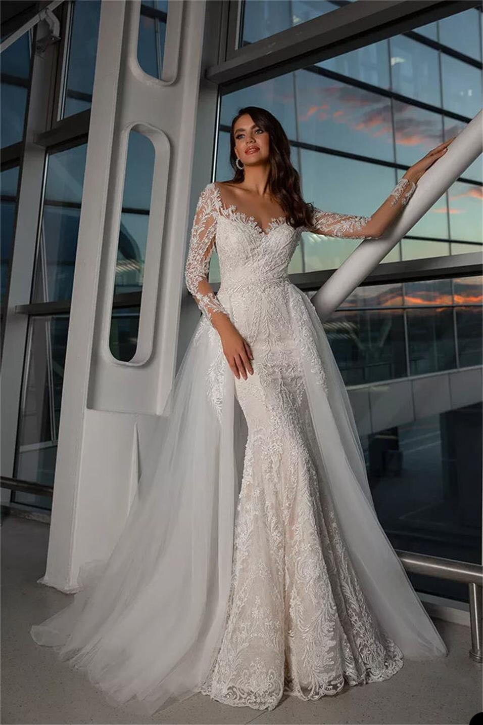 Look like a goddess in the Robe Adriene, a luxury bridal gown with dazzling crystal accents and a gorgeous mermaid silhouette. With its soft and flowing long sleeves, you'll feel beautiful and graceful as you make your grand entrance. Make a stunning impression on your special day!