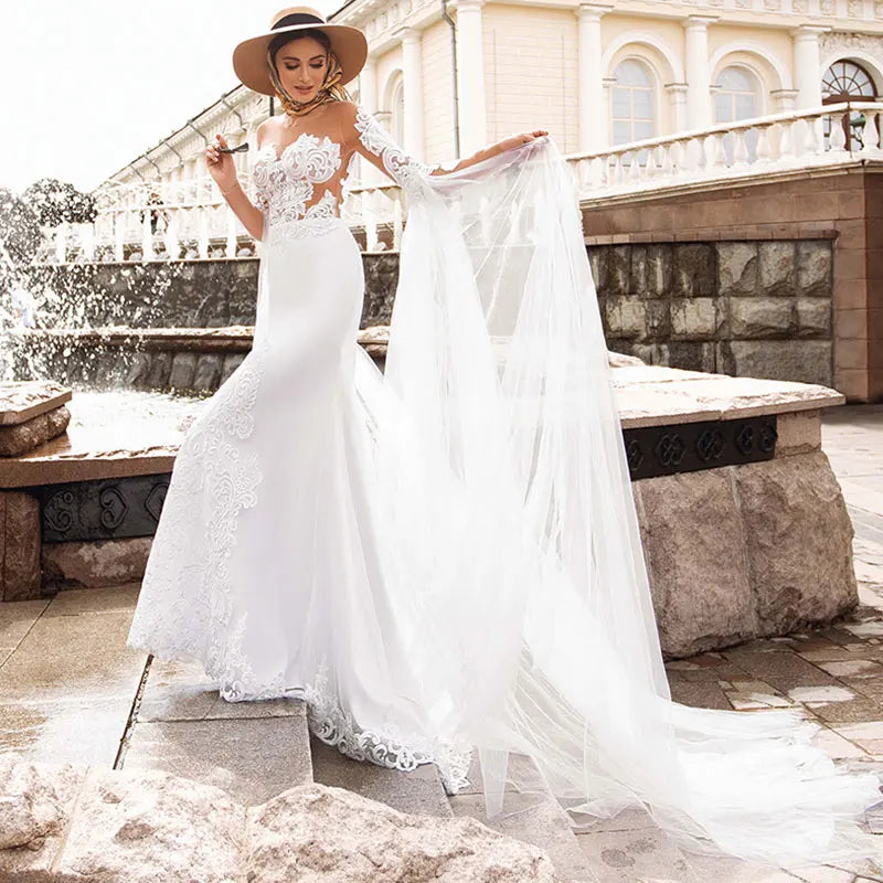 Introducing the Robe Lunete - a boho mermaid wedding dress that will make you feel like a mermaid queen! Featuring delicate lace appliques, illusion tulle, and stylish long sleeves, this dress is the perfect choice for a bride looking for a unique and stunning look on her special day. The shawl adds an extra touch of elegance and can be styled in multiple ways. Say yes to this button-up beauty!