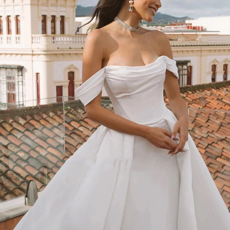 Transform into a regal vision with our Robe Bellisima. The elegant off shoulder design and detachable sleeves create a princess-like silhouette, perfect for a ball gown wedding. Crafted with luxurious detail and customizable for a flawless fit. Be a true queen on your special day.