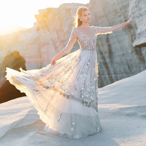 Experience the magic of a star studded night in our stunning Pauline Robe! This three-quarter sleeved gown boasts an A-line silhouette, V-neckline, and backless design. Sheer tulle with sparkling accents creates a beautiful and romantic look perfect for your wedding day. Capture stunning memories in this unique and gorgeous bridal gown!