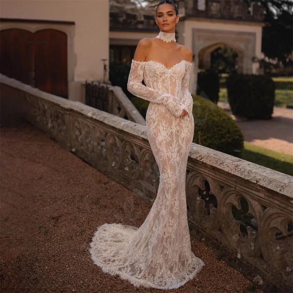 The Robe Rosalinda combines intricate lace details with a mermaid silhouette for a charming and elegant wedding dress. With long sleeves and a sweetheart neckline, this dress is perfect for a romantic and timeless look. Stand out on your special day with this stunning dress.