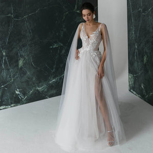 Get ready to turn heads in our Robe Nanou wedding dress. Boasting a V neck, exquisite embroidery, lace, and tulle, this A Line gown is custom-made to perfection. Leave a lasting impression with its open back, elegant pearls, and see-through detailing. The high split shoulder train adds a touch of glamour, making it the perfect choice for your special day.