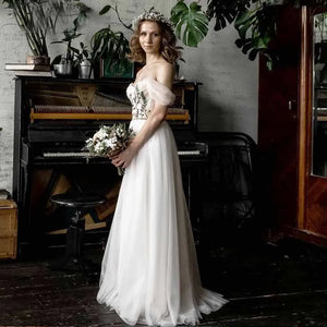 The Robe Giuliana is a stunningly crafted wedding dress, featuring intricate boho embroidery and delicate tulle blossom details. The dress boasts a sweet off shoulder neckline, adding a touch of romance to any wedding look. Exude elegance and grace on your special day with this beautiful and unique piece.