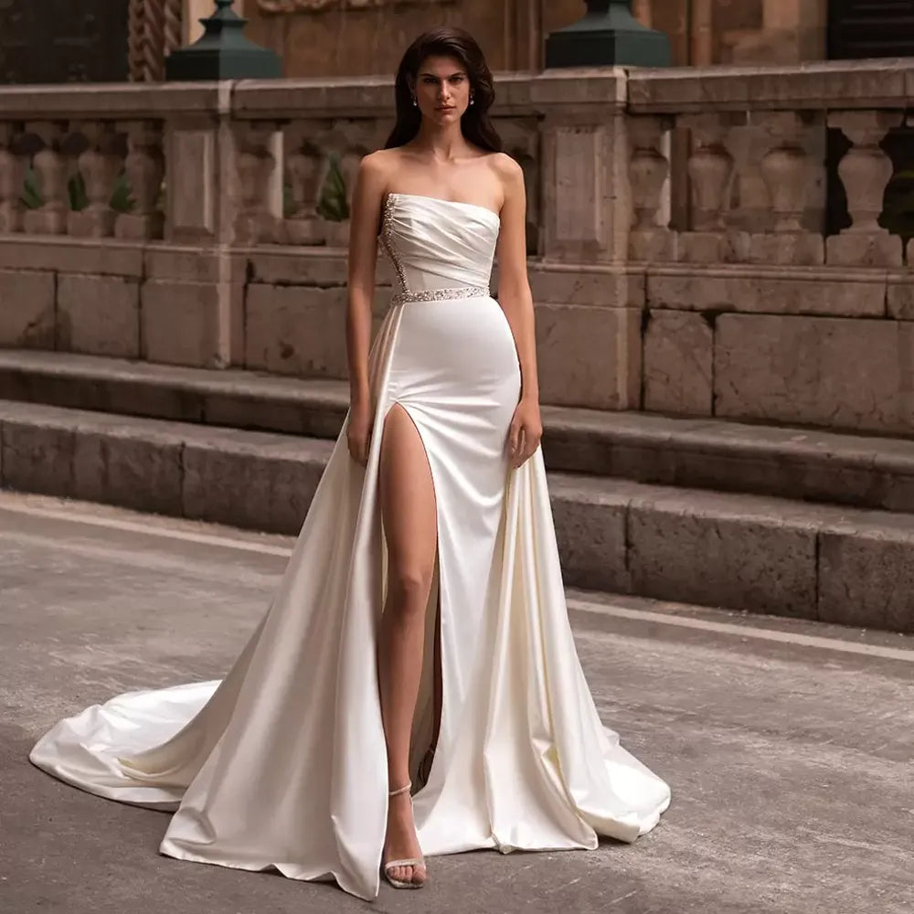 Beautifully crafted, the Robe Corinne wedding dress is a magnificent one-shoulder gown with a slit skirt and A Line silhouette, topped off with a detachable train for added drama. This regal bridal gown is sure to make heads turn and capture all the attention on your special day.