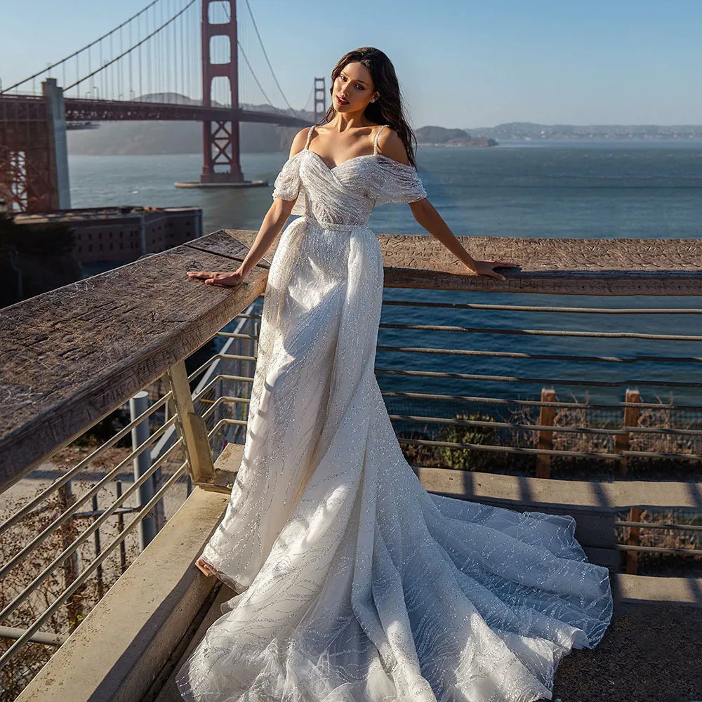 The Robe Tracy is a stunning Glitter Mermaid Wedding Dress with a detachable train and an off shoulder design. With its sparkly details, it will make any bride feel like a mermaid princess on her special day. Its unique features provide both style and convenience, making it a must-have for any bride-to-be.